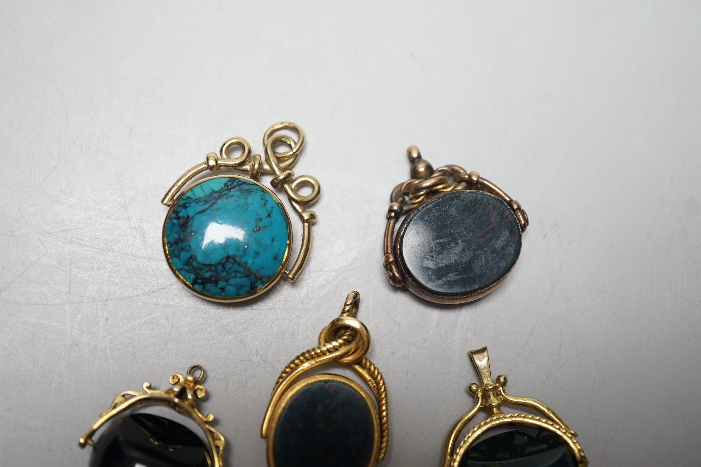 A late Victorian 18ct gold mounted bloodstone and carnelian set spinning fob seal, 36mm, a similar 9ct seal, a yellow metal and turquoise set fob seal and two later 9ct gold mounted seals.